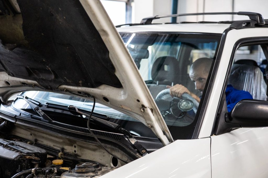 services-03 A mechanic performs a detailed inspection on a vehicle in a workshop setting.